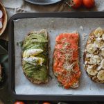 Tray of three assorted open-faced sandwiches with fresh toppings for a delicious meal.