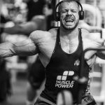 Muscular man intensely working out with gym equipment, showcasing strength and focus.